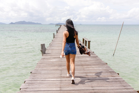 girl walking on wooden bridge extended into the seaの写真素材