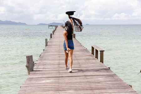 girl walking on wooden bridge extended into the seaの写真素材