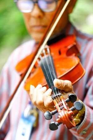 Thailand - September 10, 2017 An old man playing violin at the parking areaの写真素材