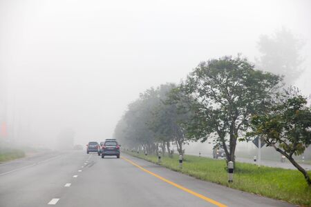 Blurred hard foggy road with detail of car light, travel in winter, car or dangerous winter transportation concept.の写真素材