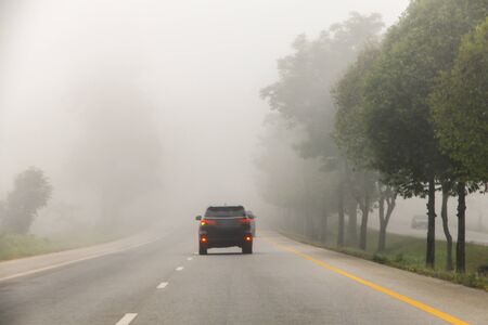 Blurred hard foggy road with detail of car light, travel in winter, car or dangerous winter transportation concept.の写真素材