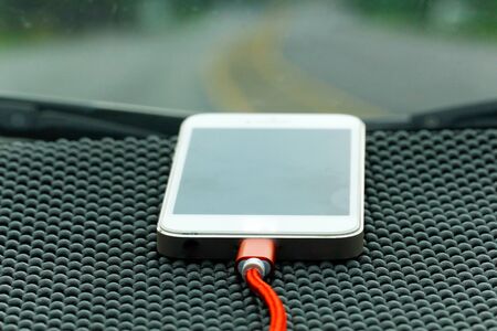 Smartphone charging with charger in car on Console boardの写真素材