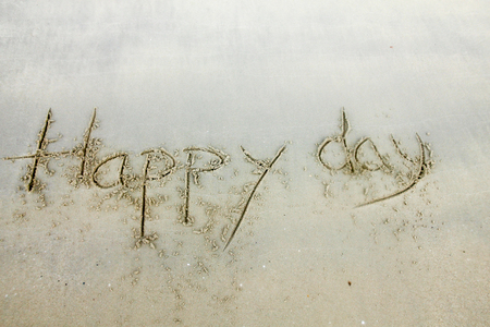 Handwriting words HAPPY DAY." on sand of beach.の写真素材