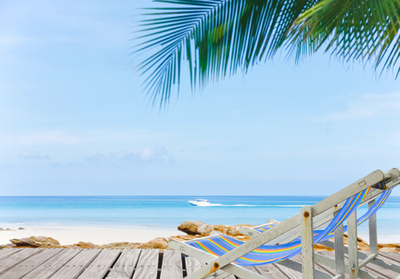chaise longues at the beach with clear skies and palm trees.Summer Holidays background. Palm leaves, fluffy clouds, blue sea, white sand. Tropical beach.の写真素材