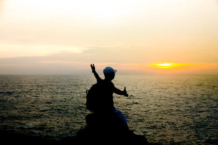 Silhouette of a men siting in front of sun in early morning at the time of sunriseの写真素材