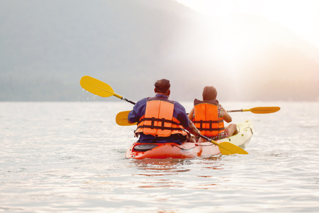 Travel concept with family swimming in sea on kyak at sunset backdrop.の写真素材
