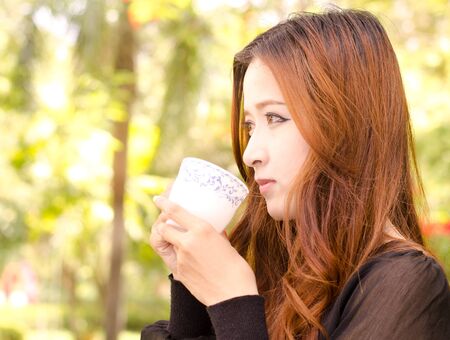 Close up beautiful asian woman holding coffee cup in morning timeの写真素材