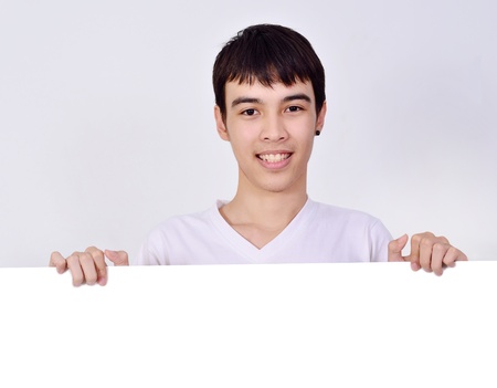 Smiling young  man holding white sign to write it on your text isolated on white backgroundの写真素材