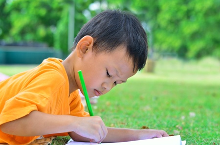 Going back to school  Cloe up Boy drawing and painting over green grass backgroundの写真素材
