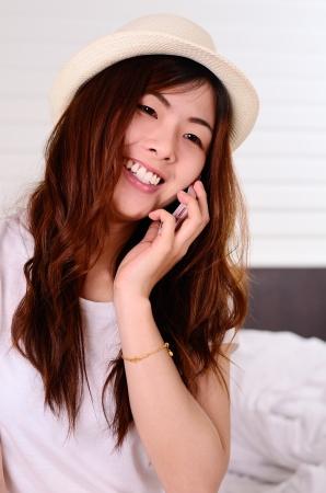 Asian teenage talking and chat with cellphone in bedroomの写真素材