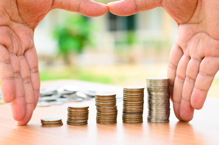 Male hand protect money coins stack with home as saving for home conceptの写真素材