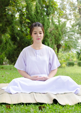 meditation woman nature,Buddhist thai woman happy with white clothing sitting for concentration on green grass background.の写真素材