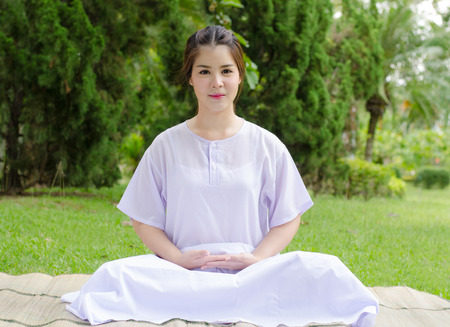 meditation woman nature,Buddhist thai woman happy with white clothing sitting for concentration on green grass background.の写真素材