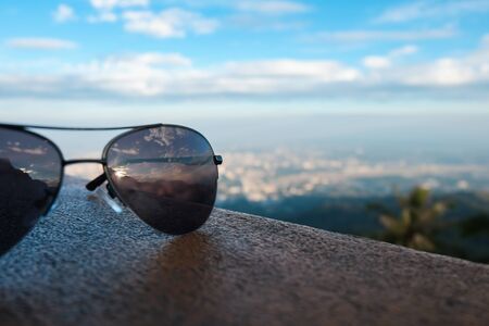 Sunglasses reflect the sunset on the wall, high mountains, sky and beautiful cityの写真素材