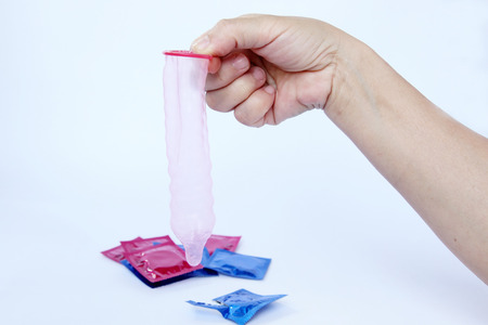 female hand holding condom isolated on white background の写真素材