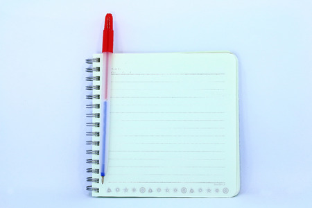 Ballpoint pen resting on a blank note pad isolated on whiteの写真素材