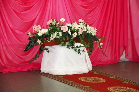 Bouquet of artificial flowers in pot at background of pink drapesの写真素材
