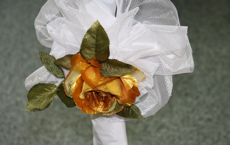 Beautiful artificial golden rose with green leaves and decorationsの写真素材