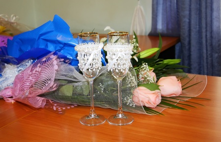 Two beautiful decorated wedding glasses and flowers on tableの写真素材