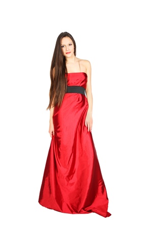 Young girl wearing long red dress stands isolated on white backgroundの写真素材
