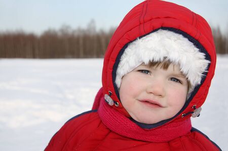 Little girl stands near forest at winter and looks into cameraの写真素材