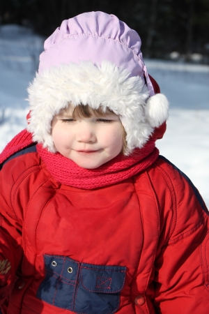 Little beautiful girl wearing warm clothing walks in winter forestの写真素材