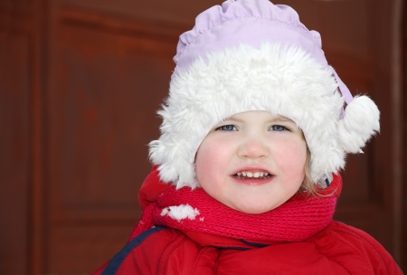 Cute little girl wearing warm clothing stands and looks at cameraの写真素材