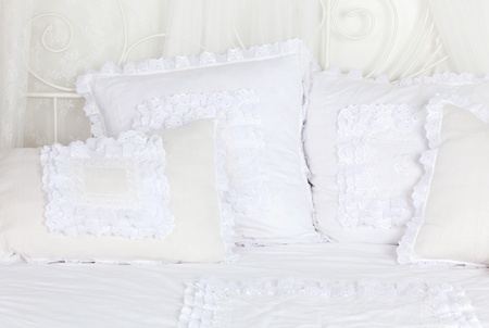 Beautiful and soft white laced pillows lie on white double bed.の写真素材