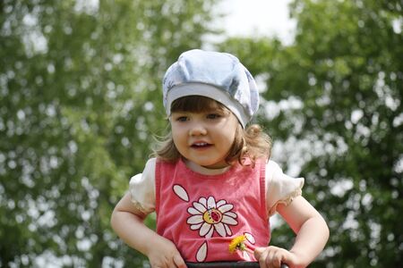 Happy little cute girl in pink dress at summer day outdoors. の写真素材