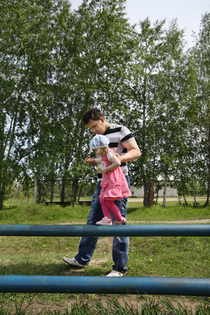 Happy little cute girl goes on pipe with her father at summer day outdoors. の写真素材