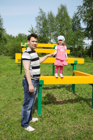 Happy little cute girl with her father at playground at summer day outdoors. の写真素材