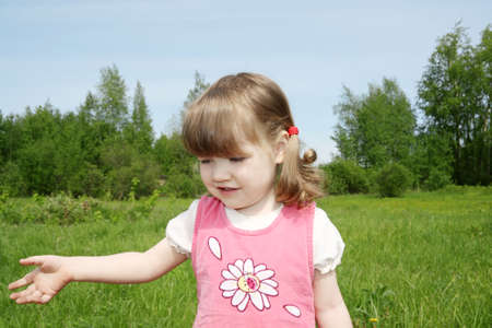 Little cute girl smiles at small field at sunny summer day outdoors. の写真素材