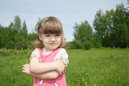 Little cute girl looks away at small field at sunny summer day outdoors. の写真素材