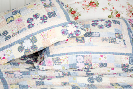 Beautiful and soft colored pillows lie on double bed with blanket.