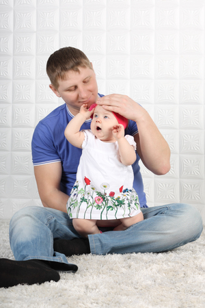 Happy young father in jeans and little baby sit on soft carpet.の写真素材