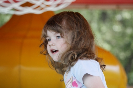 Little pretty happy girl in yellow inflatable trampoline looks away.の写真素材