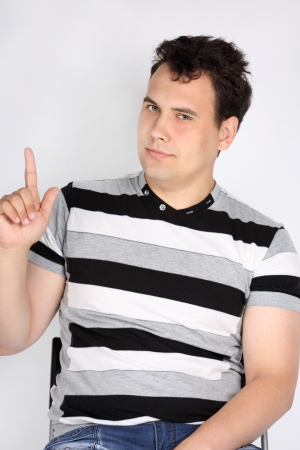 Portrait of brunet handsome smiling man with forefinger up on grey background.の写真素材