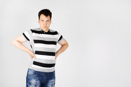 Serious man stands akimbo and looks at camera on grey background.の写真素材