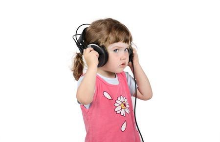 Little serious girl listens to music in big headphones isolated on white background.の写真素材