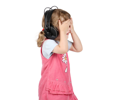 Little girl listens to music in big headphones and closed eyes by hands isolated on white background.の写真素材