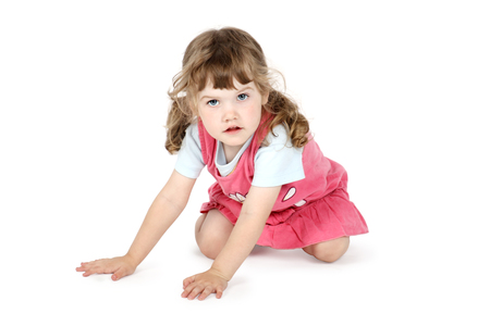 Little pretty girl sits on floor and looks at camera isolated on white background.の写真素材