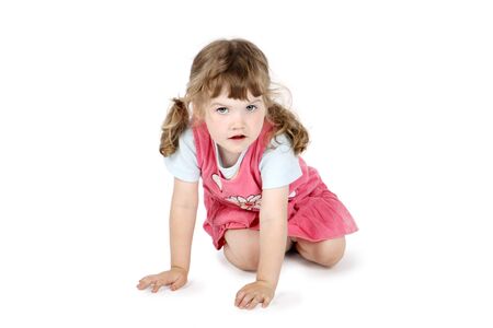 Little cute girl sits on floor and looks at camera isolated on white background.の写真素材