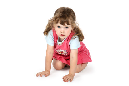Little surprised girl sits on floor and looks away isolated on white background.の写真素材