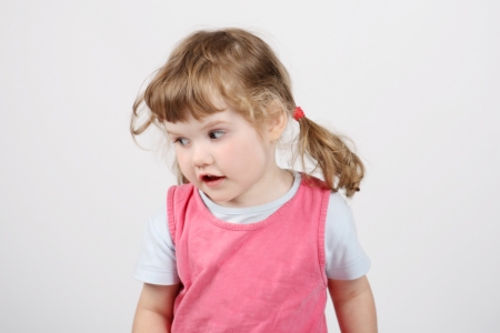 Little happy beautiful girl looks away and sings on white background.の写真素材