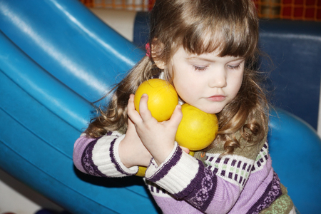 Little cute girl with yellow balls in hands on playground near slide.の写真素材