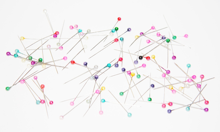 Safety pins with colored circular heads for sewing on white paper の写真素材