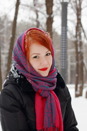 Beautiful girl in red kerchief smiles outdoor at winter day in parkの写真素材