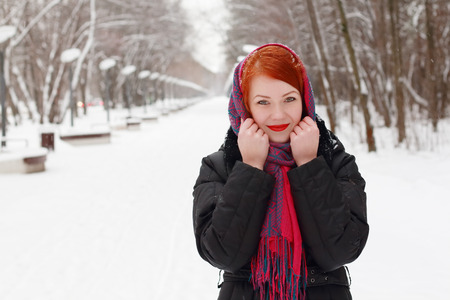 Pretty happy girl in red kerchief smiles outdoor at winter day in parkの写真素材