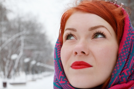Pretty happy girl in red kerchief looks up outdoor at winter day in parkの写真素材