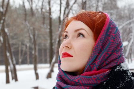 Pretty redhead girl in red kerchief looks up outdoor at winter day in parkの写真素材